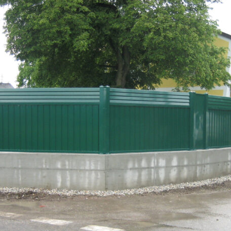 Eine grüne Metallzaun-Konstruktion mit Betonfundament umgibt einen Garten mit Baum. de HANSEL.kraus metalltechnik gmbh