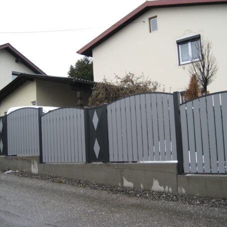 Moderner grauer Metallzaun mit Verzierungen vor zwei Einfamilienhäusern an einer ruhigen Straße. HANSEL.kraus metalltechnik gmbh