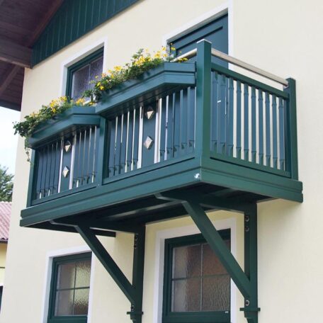 Grüner Holzbalkon mit Blumenkasten an gelber Hausfassade, Fenster darunter, typisch für Imagefilm-Produktion in Freiburg. HANSEL.kraus metalltechnik gmbh