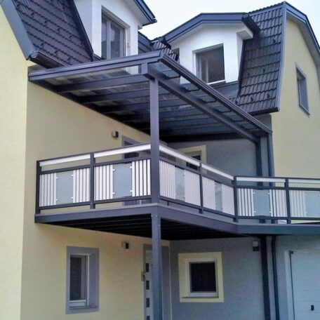 Modernes Zweifamilienhaus mit überdachtem Balkon und gelber Fassade. de HANSEL.kraus metalltechnik gmbh
