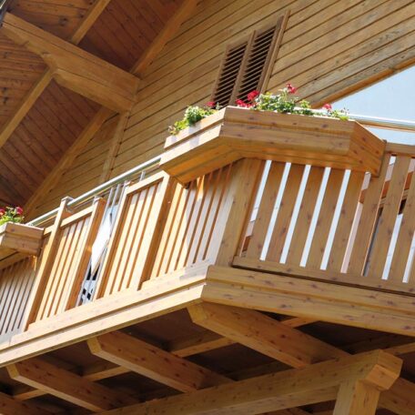 Holzbalkon mit Blumenkasten und Fenster an einem modernen Holzhaus unter schrägem Dach. HANSEL.kraus metalltechnik gmbh