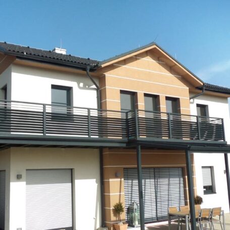 Modernes Zweifamilienhaus mit großem Balkon und Holzfassade bei sonnigem Wetter. de HANSEL.kraus metalltechnik gmbh