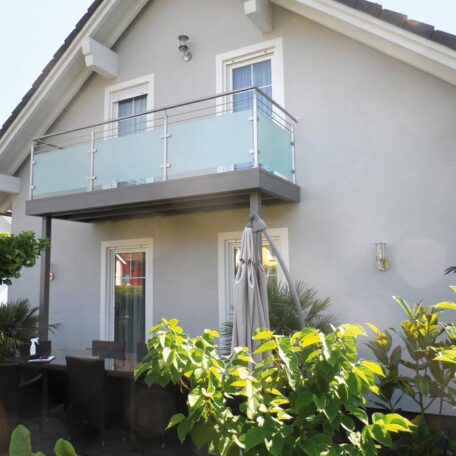 Modernes Einfamilienhaus mit Balkon, Glasgeländer und Garten, Aufnahme bei Tageslicht. HANSEL.kraus metalltechnik gmbh
