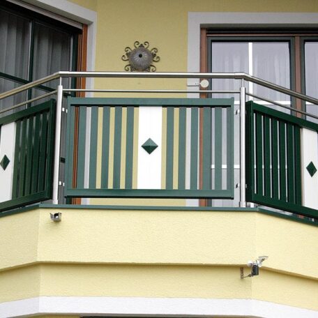 Grünes und weißes Balkongeländer aus Metall an gelber Hausfassade, modernes Design. HANSEL.kraus metalltechnik gmbh