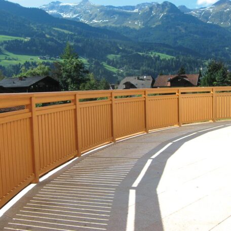 Holzzaun auf Terrasse mit Blick auf grüne Berge und sonnige Landschaft. HANSEL.kraus metalltechnik gmbh
