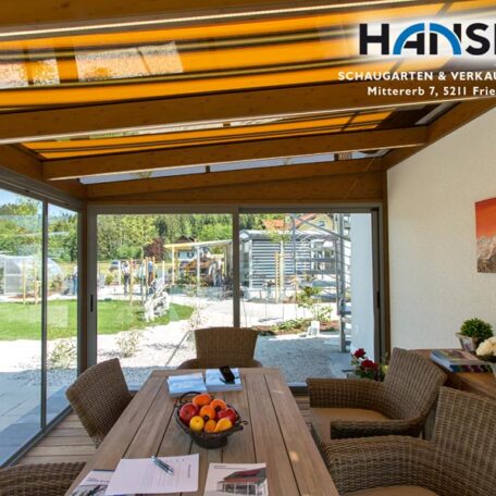 Gemütlicher Wintergarten mit Holztisch, Korbstühlen und Blick in den sonnigen Garten. HANSEL.kraus metalltechnik gmbh