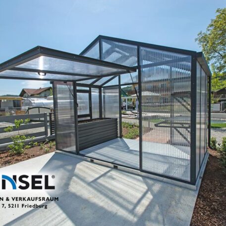 Modernes Metall-Gewächshaus mit Schiebetür steht auf Betonplatte im sonnigen Garten. de HANSEL.kraus metalltechnik gmbh