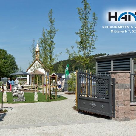 Gepflegter Garten mit Tor, Spielplatz und Infotafeln unter blauem Himmel, Messegelände HANSA. HANSEL.kraus metalltechnik gmbh