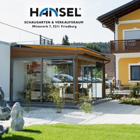 Moderner Wintergarten-Anbau mit Glasfront an gelbem Wohnhaus, gepflegter Garten im Vordergrund. HANSEL.kraus metalltechnik gmbh