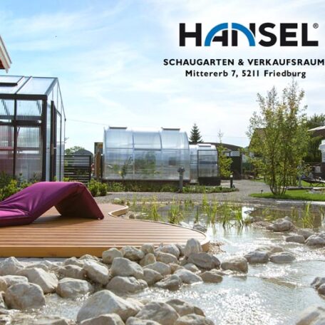 Modern gestalteter Schaugarten mit Holzdeck, Teich, Felsen und Gewächshaus in Freiburg, Hansel Logo sichtbar. de HANSEL.kraus metalltechnik gmbh