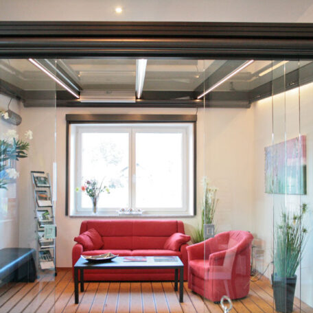 Heller Raum mit rotem Sofa, Sessel, Glastisch und Pflanzen, modernes Büroambiente. HANSEL.kraus metalltechnik gmbh