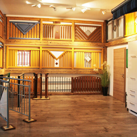 Ausstellungsraum werden verschiedene Holzgeländer, Türen und Zäune auf Holzboden präsentiert. HANSEL.kraus metalltechnik gmbh