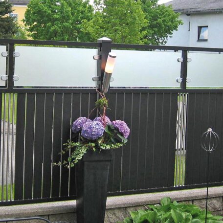 Lila Hortensien in einem schwarzen Pflanzkübel vor einem Sichtschutzzaun im Garten. HANSEL.kraus metalltechnik gmbh