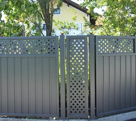 Moderner anthrazitfarbener Gartenzaun mit dekorativen Sichtschutz-Elementen vor grünem Garten, Haus im Hintergrund. de HANSEL.kraus metalltechnik gmbh