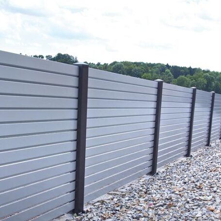 Moderner Sichtschutzzaun aus Metall mit Kiesbett vor einer grünen Landschaft. de HANSEL.kraus metalltechnik gmbh