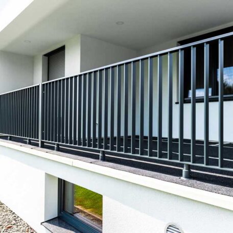 Moderner Balkon mit schwarzem Metallgeländer an weißer Hausfassade, klar und minimalistisch gestaltet. de HANSEL.kraus metalltechnik gmbh