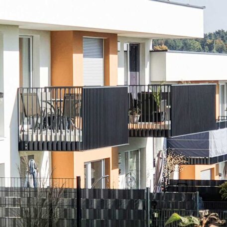 Moderne Wohnanlage mit Balkonen und orange-weißer Fassade, sonniger Tag, Freiburg. HANSEL.kraus metalltechnik gmbh