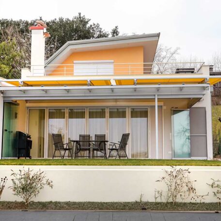 Modernes Einfamilienhaus mit Terrasse, Gartenmöbeln und Grill, umgeben von Bäumen, Tageslicht. de HANSEL.kraus metalltechnik gmbh