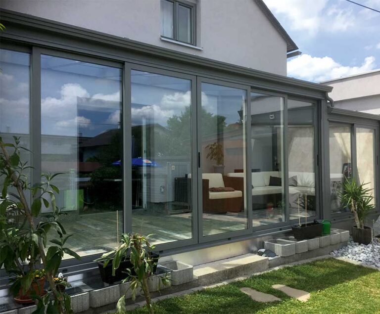 Wintergarten mit großen Glasfronten an modernem Einfamilienhaus, Terrasse mit Sitzbereich und Pflanzen. de HANSEL.kraus metalltechnik gmbh