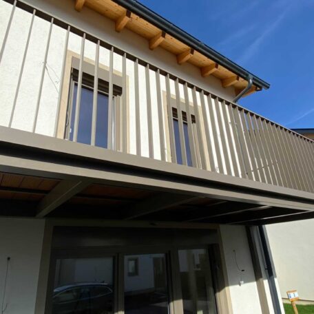 Modernes Einfamilienhaus mit Holzfassade und Balkon, aufgenommen bei blauem Himmel. de HANSEL.kraus metalltechnik gmbh