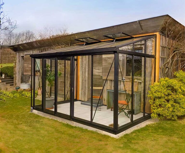 Modernes Gartenhaus mit verglastem Anbau steht vor Holzfassade im grünen Garten. de HANSEL.kraus metalltechnik gmbh