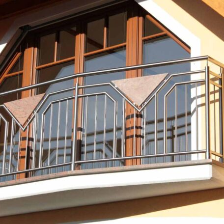 Moderner Balkon mit Metallgeländer vor großen, bogenförmigen Holzfenstern an einer Hausfassade. HANSEL.kraus metalltechnik gmbh