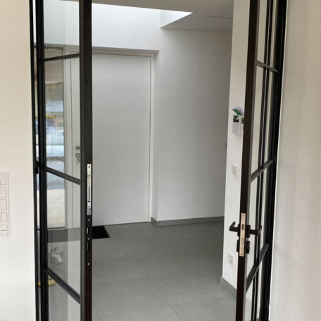 Offene Glastür mit schwarzem Rahmen führt in einen hellen, modernen Flur. HANSEL.kraus metalltechnik gmbh