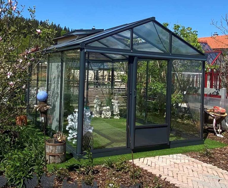 Glashaus im Garten mit Pflanzeninseln und Gartenweg bei sonnigem Wetter. HANSEL.kraus metalltechnik gmbh