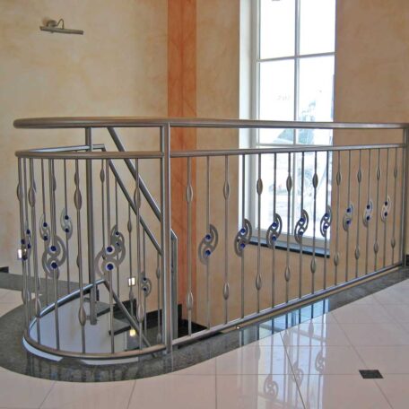 Edelstahlgeländer an einer Treppe mit geschwungenem Handlauf in hellem, modernen Treppenhaus. HANSEL.kraus metalltechnik gmbh