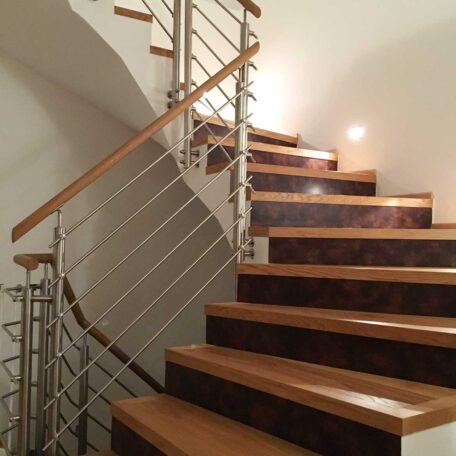 Moderne Holztreppe mit Edelstahlgeländer, indirekte Beleuchtung an der Wand, Innenbereich. HANSEL.kraus metalltechnik gmbh