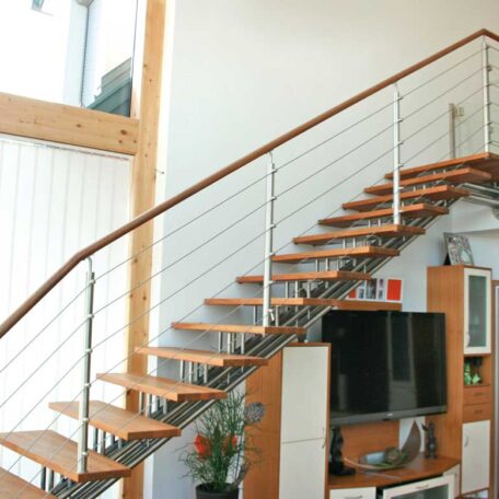 Moderne Holztreppe mit Metallgeländer in hellem Wohnzimmer, Fernseher und Regale im Hintergrund. de HANSEL.kraus metalltechnik gmbh