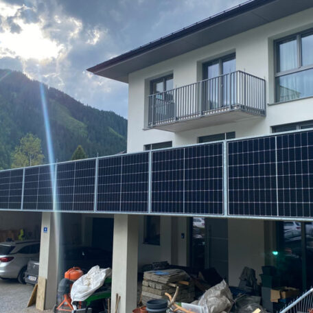 Modernes Wohnhaus mit großen Solarpanelen an der Fassade vor einer Berglandschaft im Sonnenschein. HANSEL.kraus metalltechnik gmbh