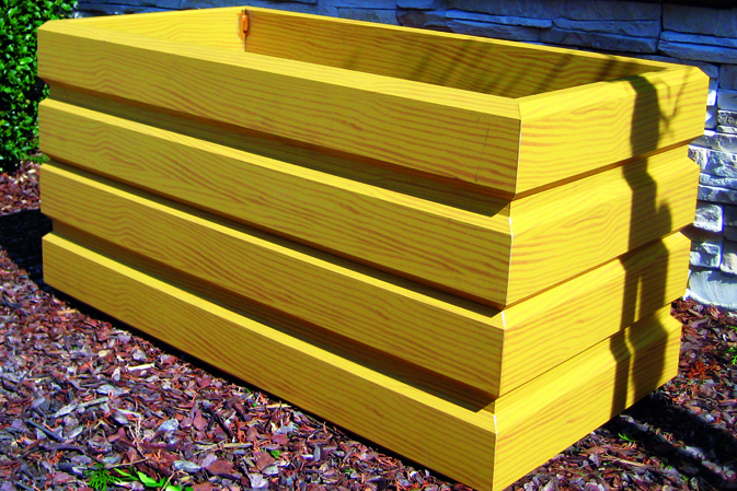 Gelbes, rechteckiges Hochbeet aus Holz steht auf steinigem Untergrund im Außenbereich. HANSEL.kraus metalltechnik gmbh