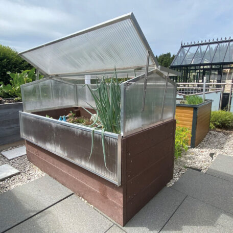 Erhöhtes Gewächshaus mit angebauten Pflanzen im Garten, Deckel offen, moderner Hintergrund. HANSEL.kraus metalltechnik gmbh