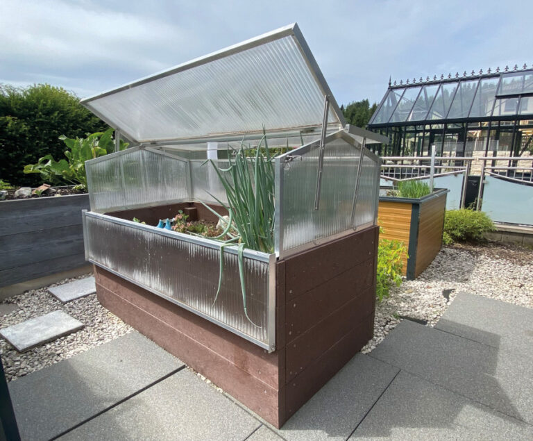 Erhöhtes Gewächshaus mit angebauten Pflanzen im Garten, Deckel offen, moderner Hintergrund. HANSEL.kraus metalltechnik gmbh