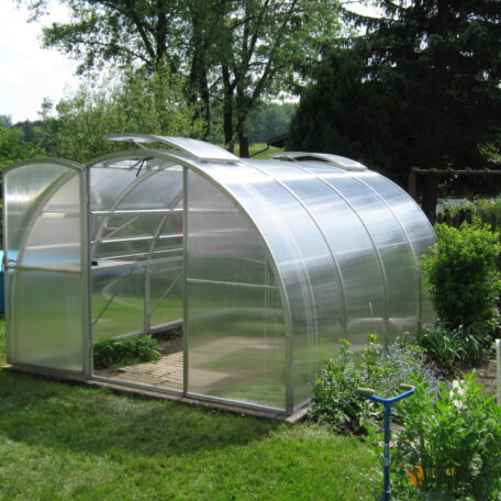 Ein modernes Gewächshaus mit durchsichtigen Wänden steht im sonnigen Garten zwischen Bäumen und Sträuchern. HANSEL.kraus metalltechnik gmbh