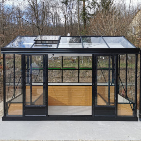 Modernes Gewächshaus aus Glas mit schwarzem Rahmen steht auf einer Terrasse im Garten. HANSEL.kraus metalltechnik gmbh