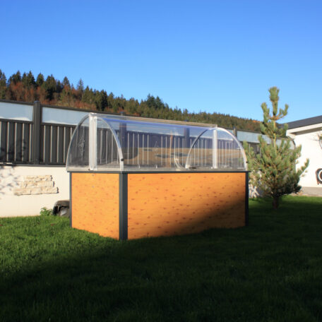 Ein Hochbeet mit transparenter Abdeckung steht im sonnigen Garten vor einem modernen Zaun. HANSEL.kraus metalltechnik gmbh