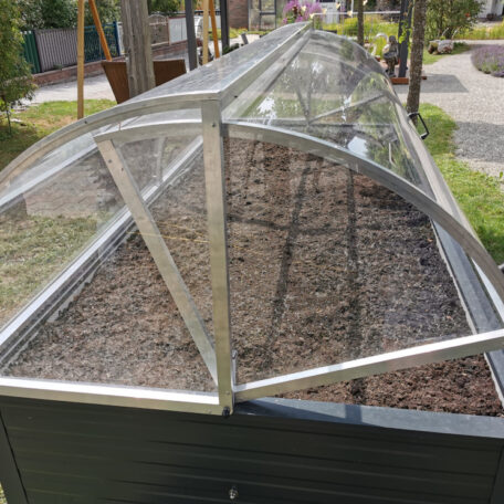 Hochbeet mit transparenter Abdeckung in einem begrünten Außenbereich, bereit zur Bepflanzung. de HANSEL.kraus metalltechnik gmbh