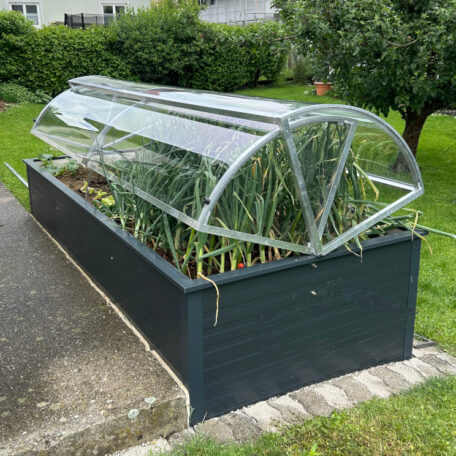 Hochbeet mit durchsichtiger Abdeckung, darin wachsen verschiedene Gemüsepflanzen im Garten. HANSEL.kraus metalltechnik gmbh