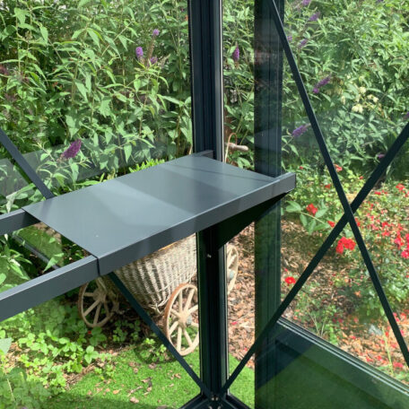 Modernes Glasgewächshaus mit Metallregal, Blick auf blühenden Garten im Hintergrund. HANSEL.kraus metalltechnik gmbh