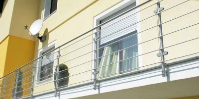 Balkon mit Metallgeländer, Fenster mit Rollladen, gelbe Hausfassade und Blumentopf. HANSEL.kraus metalltechnik gmbh