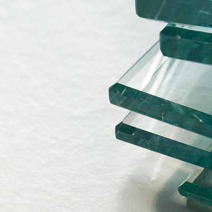 Mehrere übereinanderliegende Glasscheiben auf weißer Oberfläche, Detailaufnahme. HANSEL.kraus metalltechnik gmbh