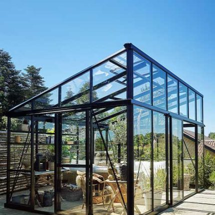 Modernes Gewächshaus aus Glas mit Pflanzen, klarer Himmel im Hintergrund, Gartenumgebung. de HANSEL.kraus metalltechnik gmbh