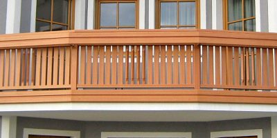 Holzbalkon mit senkrechten Streben vor zwei Fenstern, traditionelle Fassadengestaltung. HANSEL.kraus metalltechnik gmbh
