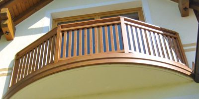 Holzbalkon mit senkrechten Streben vor Fenster eines hellen Wohnhauses. HANSEL.kraus metalltechnik gmbh