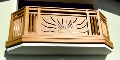 Holzgeländer mit eingeschnitztem Sonnenmotiv auf einem Balkon, modernes Handwerk. HANSEL.kraus metalltechnik gmbh