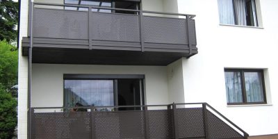 Zwei moderne Balkone mit braunen Geländern an einem weißen Mehrfamilienhaus. HANSEL.kraus metalltechnik gmbh