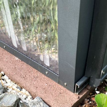 Aluminiumrahmen eines Gartenzauns auf Steinboden mit transparentem Element und Kieselsteinen. HANSEL.kraus metalltechnik gmbh