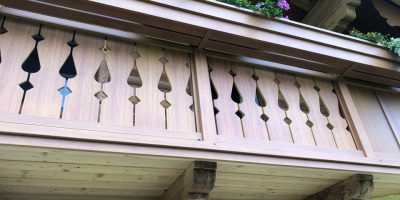 Holzbalkon mit dekorativen Schnitzereien und Blumenkasten mit lila Blüten, traditionelle Bauweise. HANSEL.kraus metalltechnik gmbh
